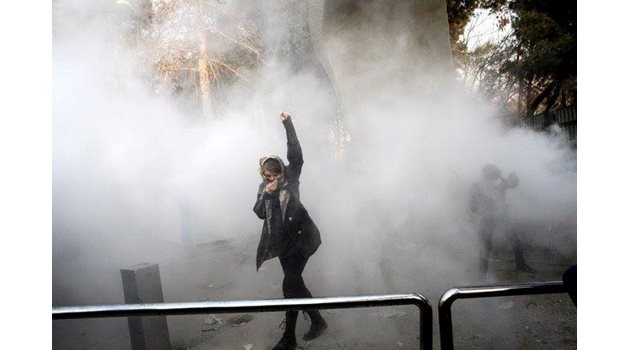 Снимка: Студентка протестира в университета в Техеран, докато отряда за борба с безредиците е хвърлил димна граната, 31 декември. Асошиейтед прес