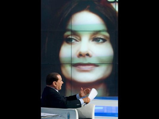 Силвио Берлускони дава интервю за тв програма пред уголемената на екран снимка на жена му Вероника.
СНИМКИ: РОЙТЕРС И АРХИВ