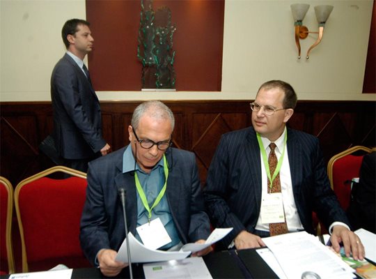 Министърът на икономиката Делян Добрев минава зад гърба на енергийния министър от правителството на НДСВ Милко Ковачев на форум за инвестиции във ВЕИ.