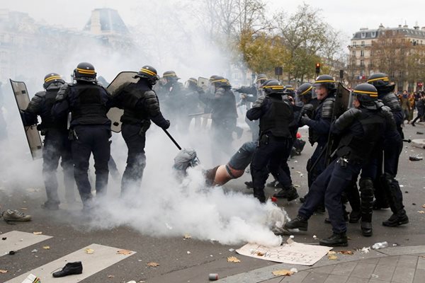 Френски полицаи хващат демонстрант по време на протестите в Париж след отмяната на планирания поход за промените в климата.