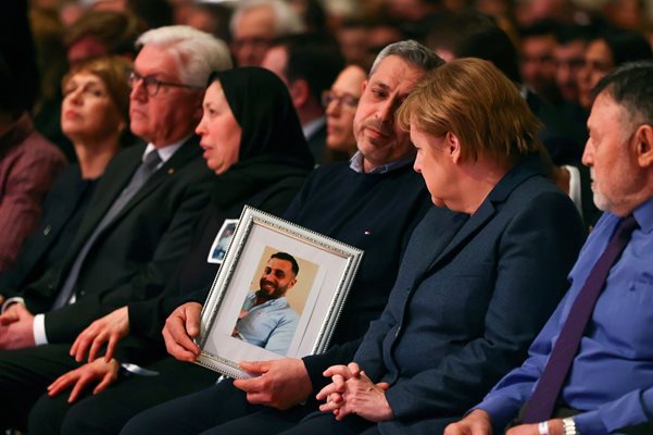 Германският канцлер Ангела Меркел гледа снимката на една от жертвите при нападенията.