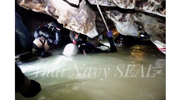 Спасители се промъкват през наводнените коридори на пещерата към затиснатите момчета.