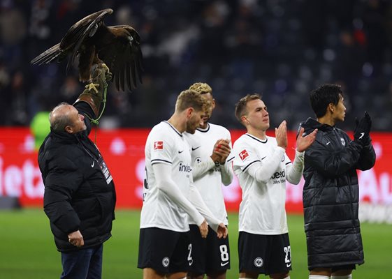 Играчите на "Айнтрахт" поздравяват феновете си след победата с 3:0 над "Шалке 04" във Франкфурт, а до тях е талисманът им - орелът Атила. С успеха "Айнтрахт" излезе на второ място във временното класиране на Бундеслигата.