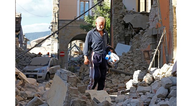 Възрастен мъж гледа тъжно останките от къщата му в Аматриче.