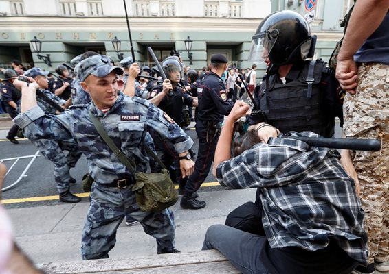 Войник от националната гвардия налага с палка демонстрант в Москва, а жандармерист го държи да не избяга.