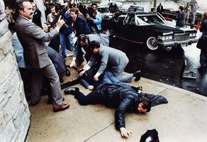 Агент на тайните служби вади своя пистолет, докато други се нахвърлят над Джон Хинкли секунди след като извършва опита за убийството на 30 март 1981 г.