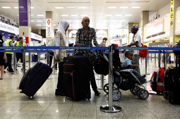 Мигранти от Африка на опашка с багажа си на летището в Малта.