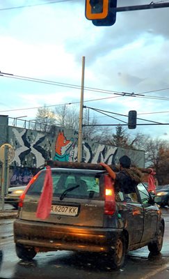 Човек крепи желязен прът с ръце върху покрива на автомобил