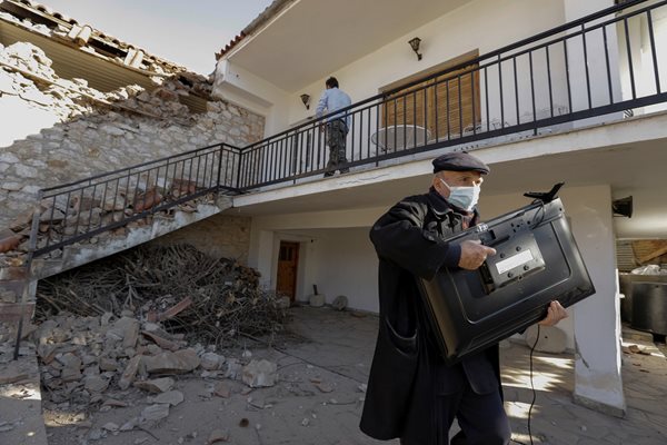 Мъж спасява телевизор от порутени сгради в Гърция.