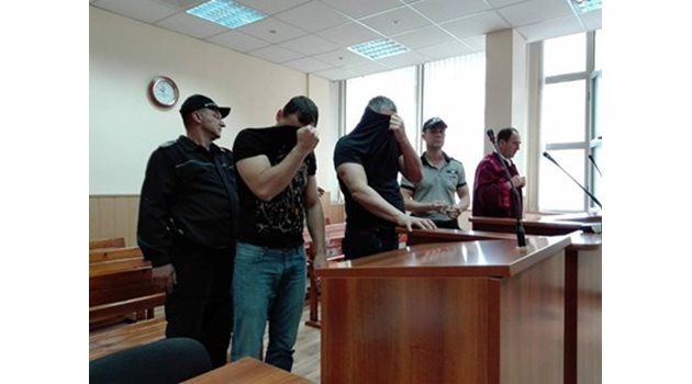 Полицаите Стефан Модев и Петър Атанасов крият лицата си в съда.