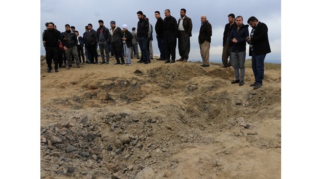 Иракчани гледат кратер, оставен от ракета, изстреляна
по базата в Ербил.