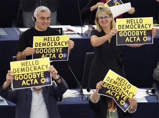 Евродепутати от фракцията на зелените празнуват с плакати след гласуването срещу АКТА.