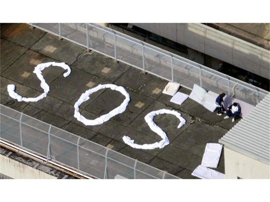 Хора са написали SOS с платна и чакат да бъдат спасени на покрива на сграда в град Кесенума. 
СНИМКИ: РОЙТЕРС
