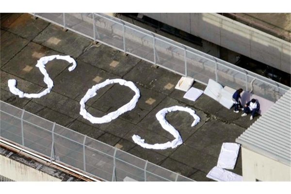 Хора са написали SOS с платна и чакат да бъдат спасени на покрива на сграда в град Кесенума. 
СНИМКИ: РОЙТЕРС
