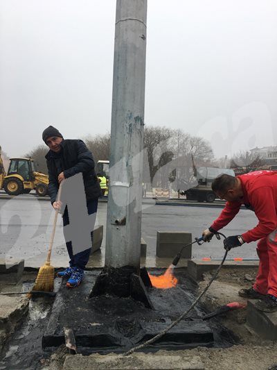 Работник избутва водата с метла, а друг с газова горелка подсушава. Снимки: Авторът