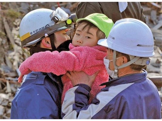 Спасители държат момиченце, намерено сред разрушенията в град Кесенума.
