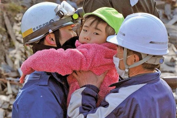 Спасители държат момиченце, намерено сред разрушенията в град Кесенума.
