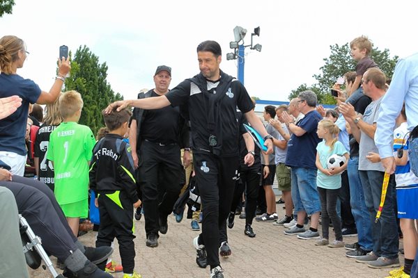 Треньорът на “Дуисбург” поздравява дете при излизане на отбора за официалното представяне на традиционния семеен ден.