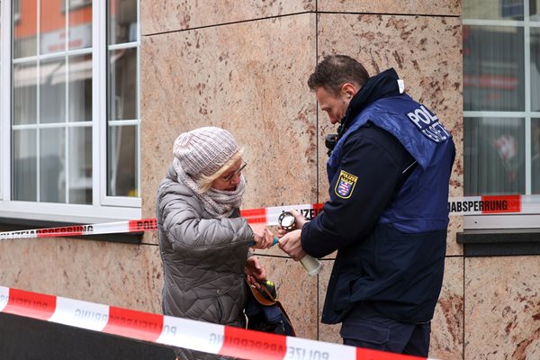 Полицай помага на германка да запали свещ до мястото на кървавото нападение.