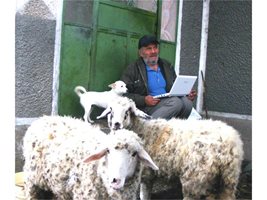 Приседнал на стълбите пред дома си, Петър чака времето да се оправи, за да изведе овцете на паша. Дотогава чати с приятел в скайпа. 
СНИМКА: АВТОРЪТ