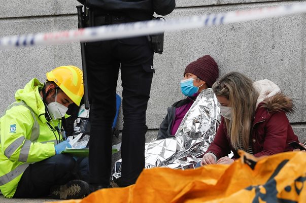 Полицай и лекар помагат на уплашени хора след експлозията.

