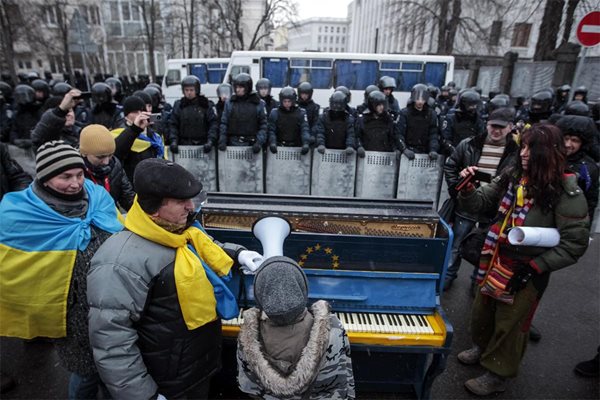 Протестиращи свирят на пиано със знамето на ЕС пред командоси на Площада на независимостта в Киев.