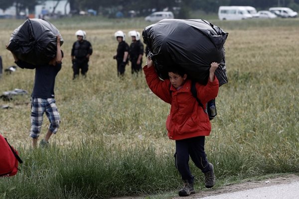 Дете от бежанско семейство носи багаж при евакуацията на лагера до Идомени.