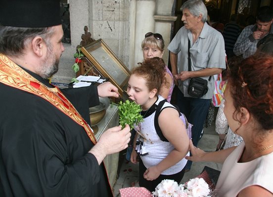 Свещеник ръси със светена вода.