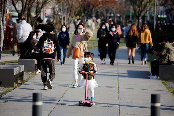 Десетки хора се разхождат в парк в Сеул.
