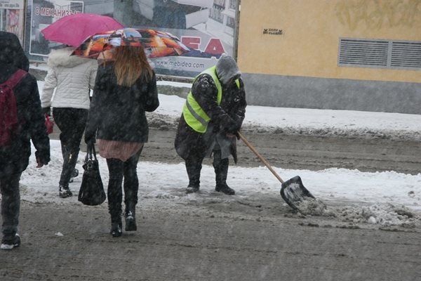 Жена от "Чистота" с гребло рине снега на главната улица в Пловдив. Снимки: Евгени Цветков