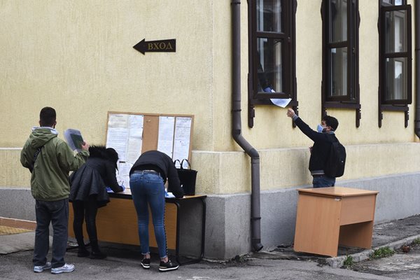 Служител на бюро по труда в София подава през прозореца документите на безработен,  дошъл да се  регистрира.