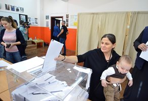 Млада жена гласува с малкото си дете.