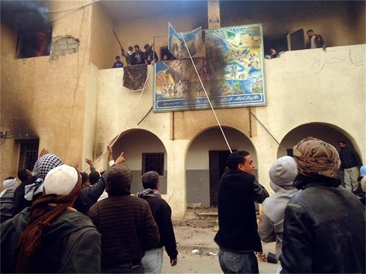 Либийски демонстранти свалят надпис от правителствена сграда в пристанището Тобрук. СНИМКИ: РОЙТЕРС
