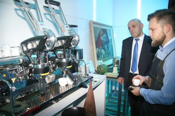 Вицепремиерът Томислав Дончев наблюдава как се прави кафето с най-авангардната машина на щанда на “Елпром Троян”.