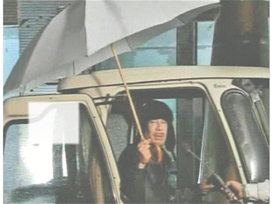 Либийският лидер Муамар Кадафи се появи по телевизията, седнал в кола и разтворил чадър. Той обяви, че не е напускал страната. СНИМКИ: ДЕСИСЛАВА КУЛЕЛИЕВА И РОЙТЕРС

