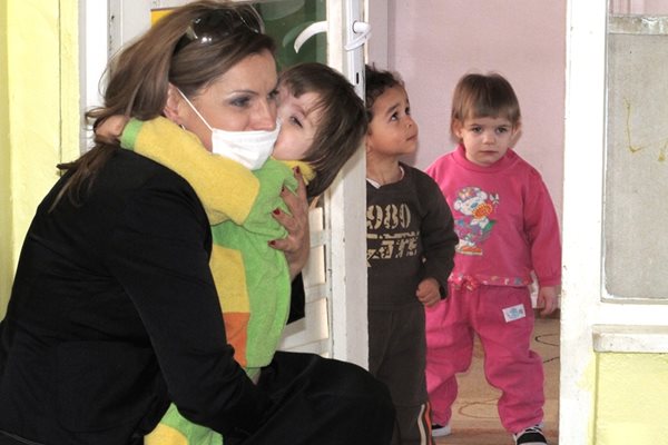 Ани Салич прегръща дете, докато е в детски дом като репортерка за благотворителното тв предаване на Би Ти Ви “Великолепната шесторка”.