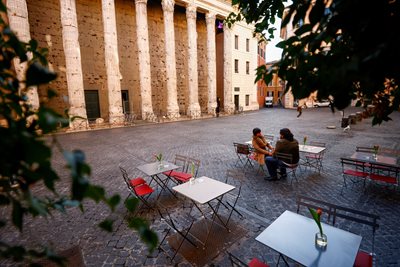 Women are sitting outdoors in an empty cafe in Rome.  PHOTO: Reuters