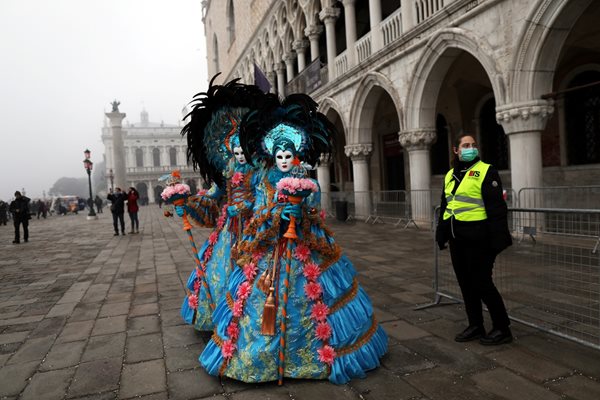 Полицайка  стои край маскирани венецианки в града на гондолите, където карнавалът беше отменен, а пл. “Сан Марко” беше затворен.