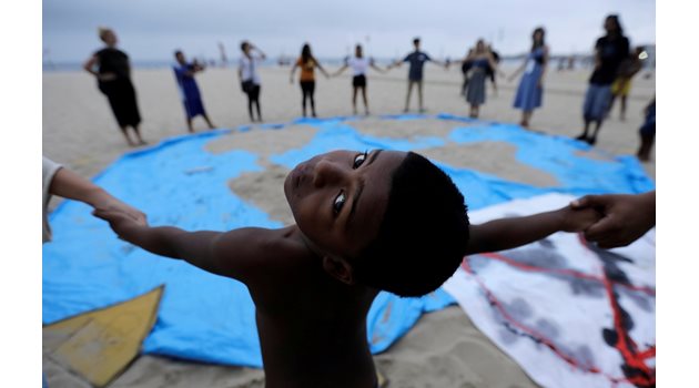 Дете е сред десетките активисти, които протестират за действия относно климатичните промени на плаж в Рио де Жанейро.