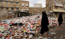 Жени ходят покрай купчини боклук. Сметосъбирачи протестират, заради закъснели заплати в Саная, Йемен