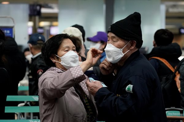 Възрастни южнокорейци си оправят маските на летището в град Инчон.