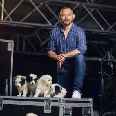 Орлин Павлов, който ще участва на благотворителния концерт, се снима с кученца от фондацията.