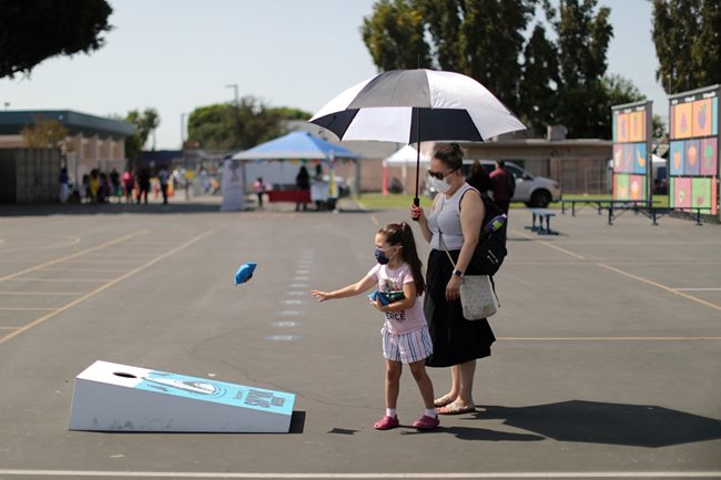 Майка играе с детето си в училищен двор до клиника за болни от коронавирус в Лос Анджелис.