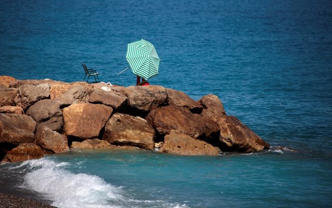 Жена опъва чадъра си на скали в топъл слънчев ден в Ница, Франция Снимки: Ройтерс