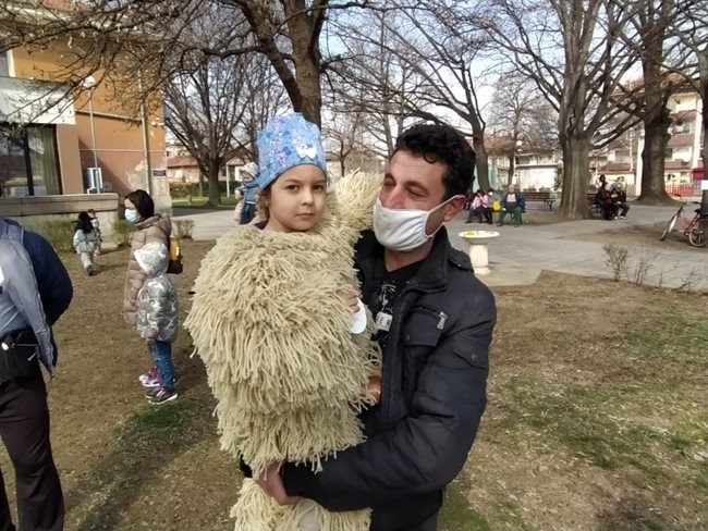 Баща е довел детето си, пременено като кукерче.