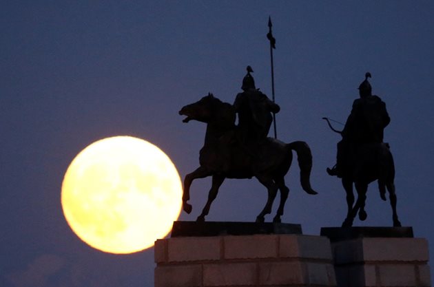 Луната е изгряла зад паметника на казахстанските народни герои и воини в Алмати, Казахстан