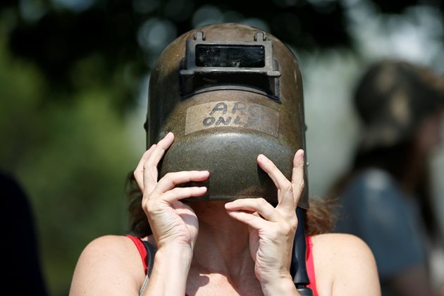 Жена наблюдава с каска на оксиженист затъмнението в Отава, Канада.