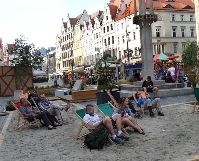 На площада във Вроцлав има пясък и шезлонги, където хората си почиват.