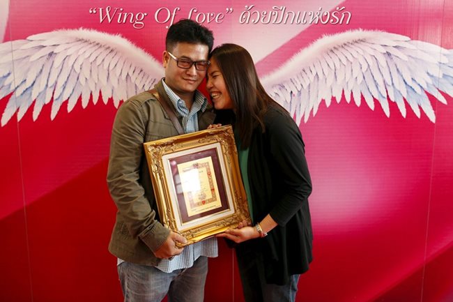 Двойка представя позлатен сертификат за любовта си в Банкок,Тайланд.