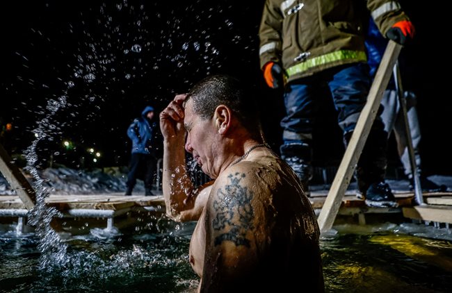 Мъж прави кръстен знак преди да се потопи в ледени води по време на чествания на православния християнски празник Богоявление